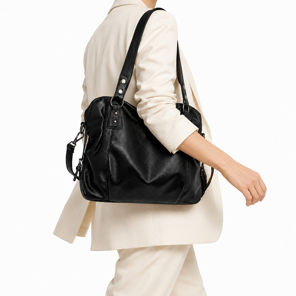 Sac bandoulière noir en polyester et TPU, grand format, avec rivets décoratifs et fermeture éclair, porté par une femme.