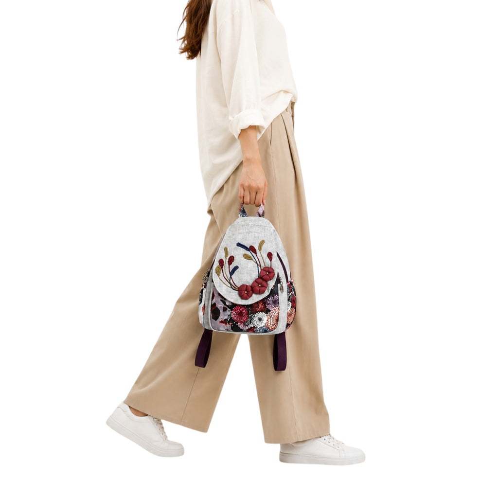 Sac à dos Univers Sac en lin gris avec broderies florales colorées et détails appliqués porté par une femme