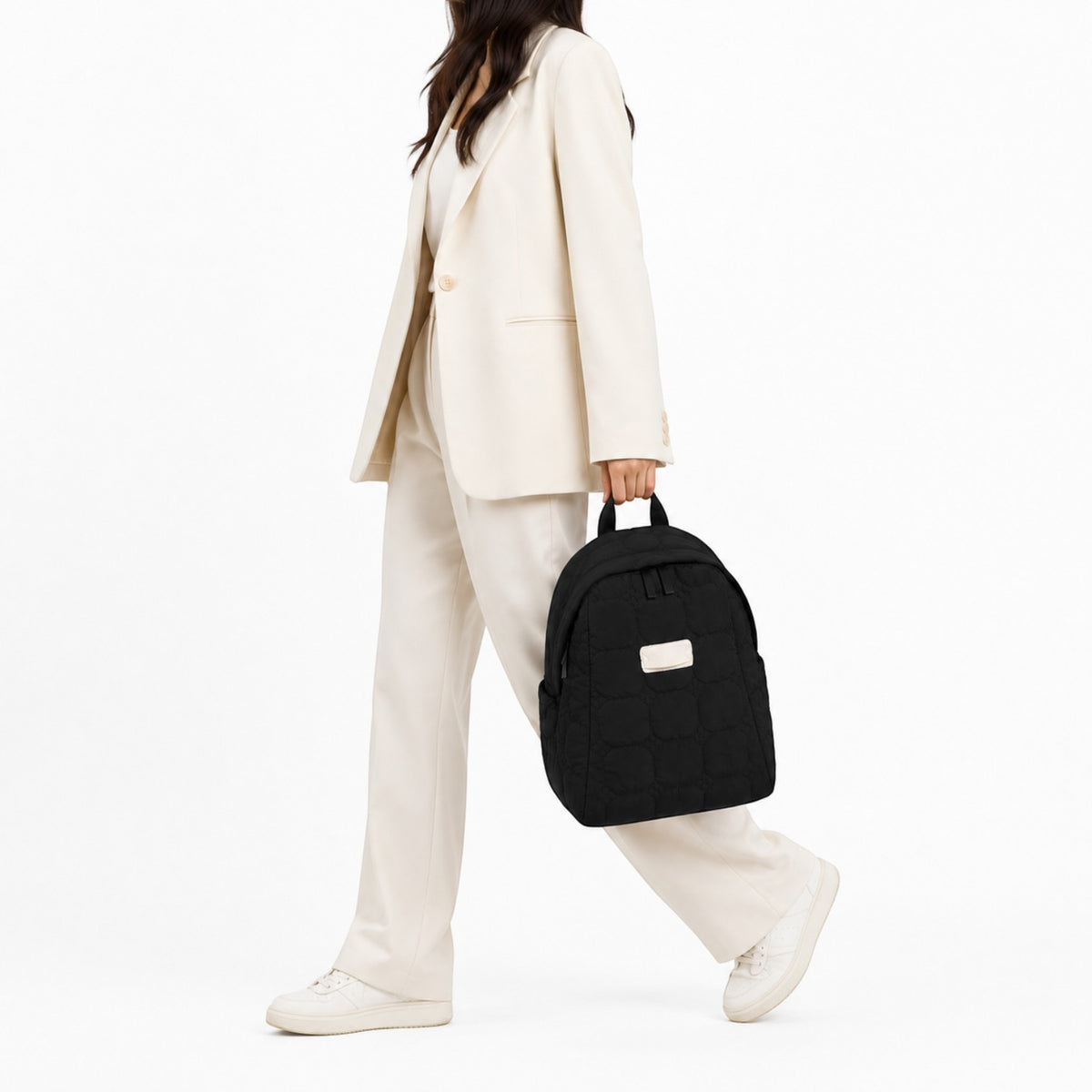Sac à dos matelassé noir Univers Sac porté par une femme en tailleur beige, style décontracté et élégant