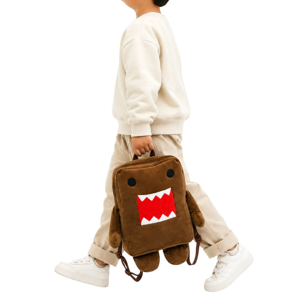 Sac à dos en peluche marron Univers Sac représentant le personnage Domo Kun, porté à la main par un enfant