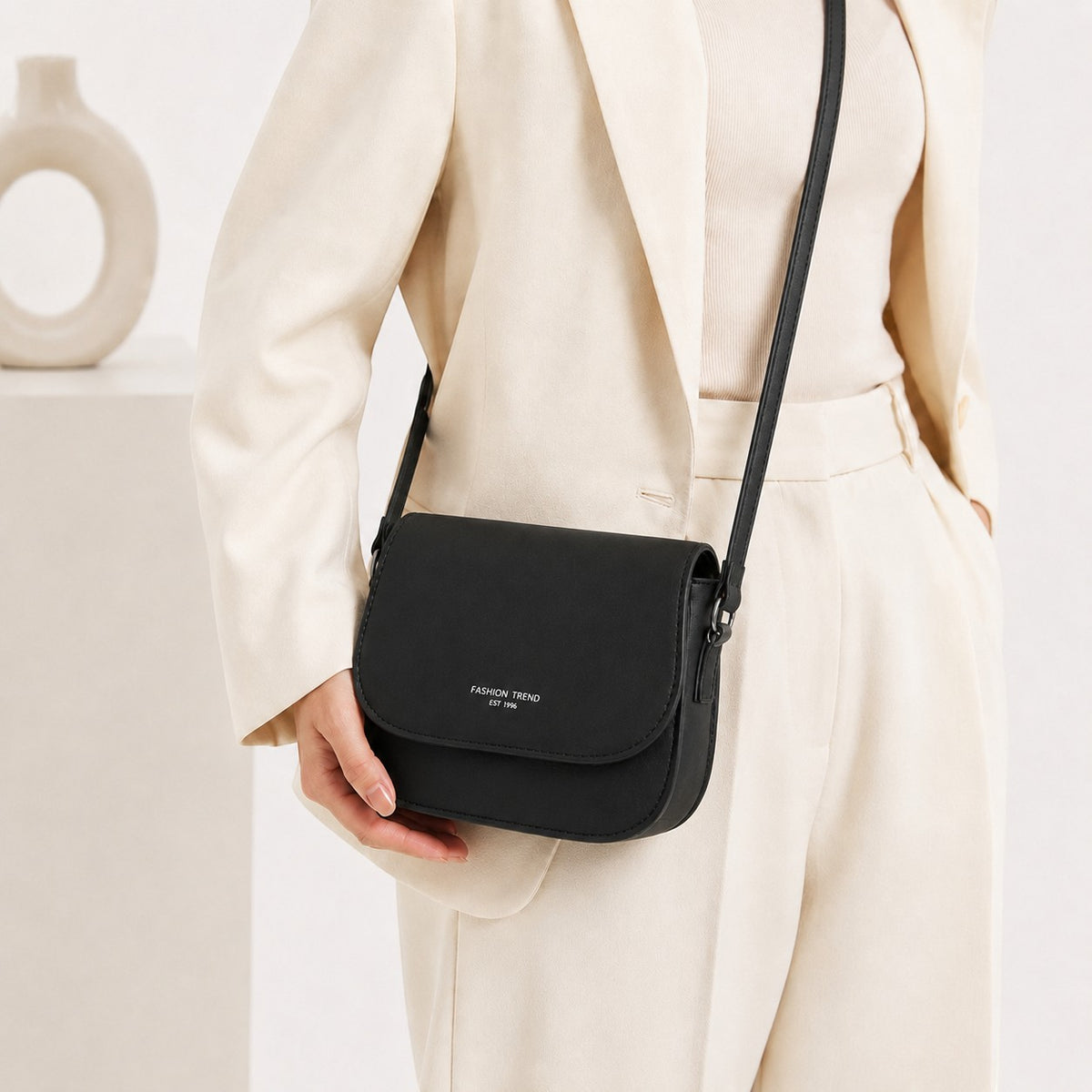 Sac bandoulière noir en cuir PU souple Univers Sac, forme carrée, avec inscription 'Fashion Trend Est 1996'.