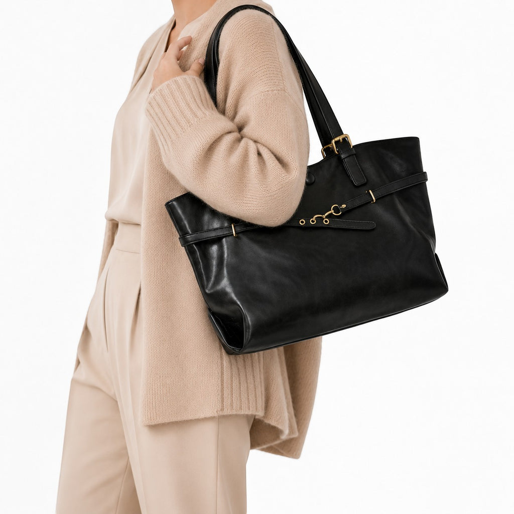 Sac bandoulière noir en cuir PU souple, style rétro avec fermoir à fermoir et détails dorés, porté par une femme.