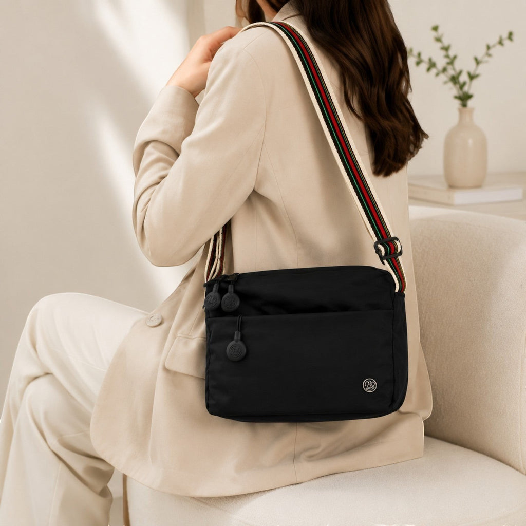 Sac bandoulière noir en nylon et coton bio, ultra léger, avec fermeture éclair et bandoulière rayée multicolore. Univers Sac.