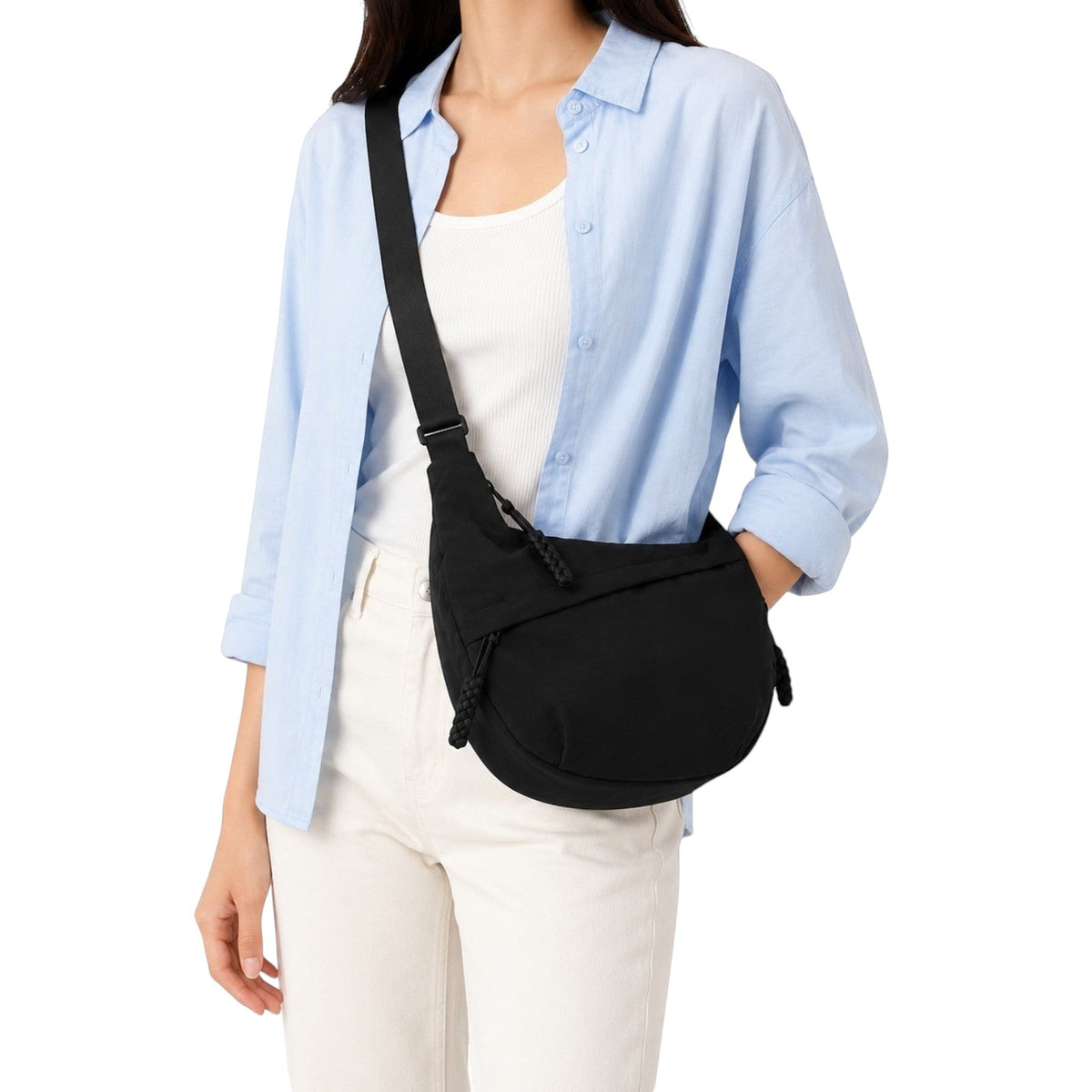Sac bandoulière noir en nylon avec fermeture éclair et poche extérieure ouverte, porté par une femme.