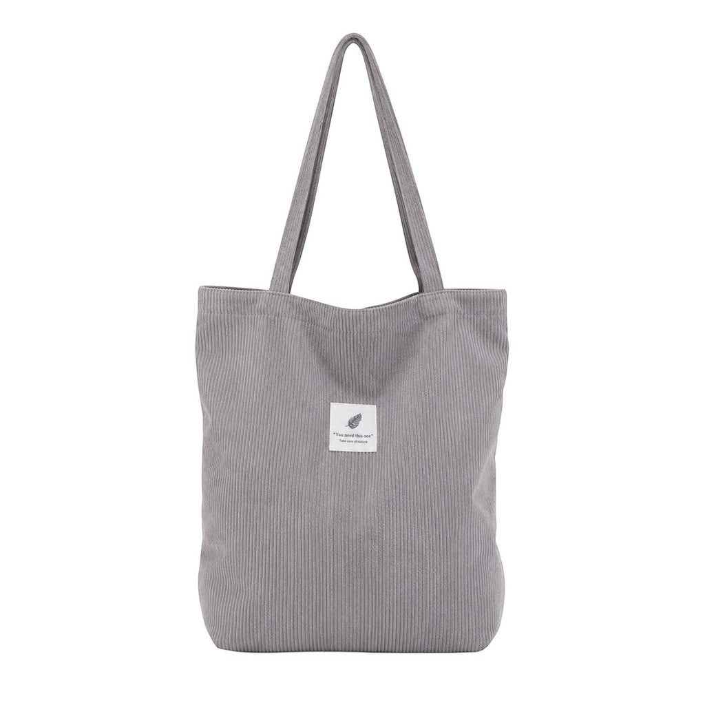 Sac fourre-tout gris en velours côtelé souple avec deux anses et une poche intérieure zippée. Idéal pour femmes.