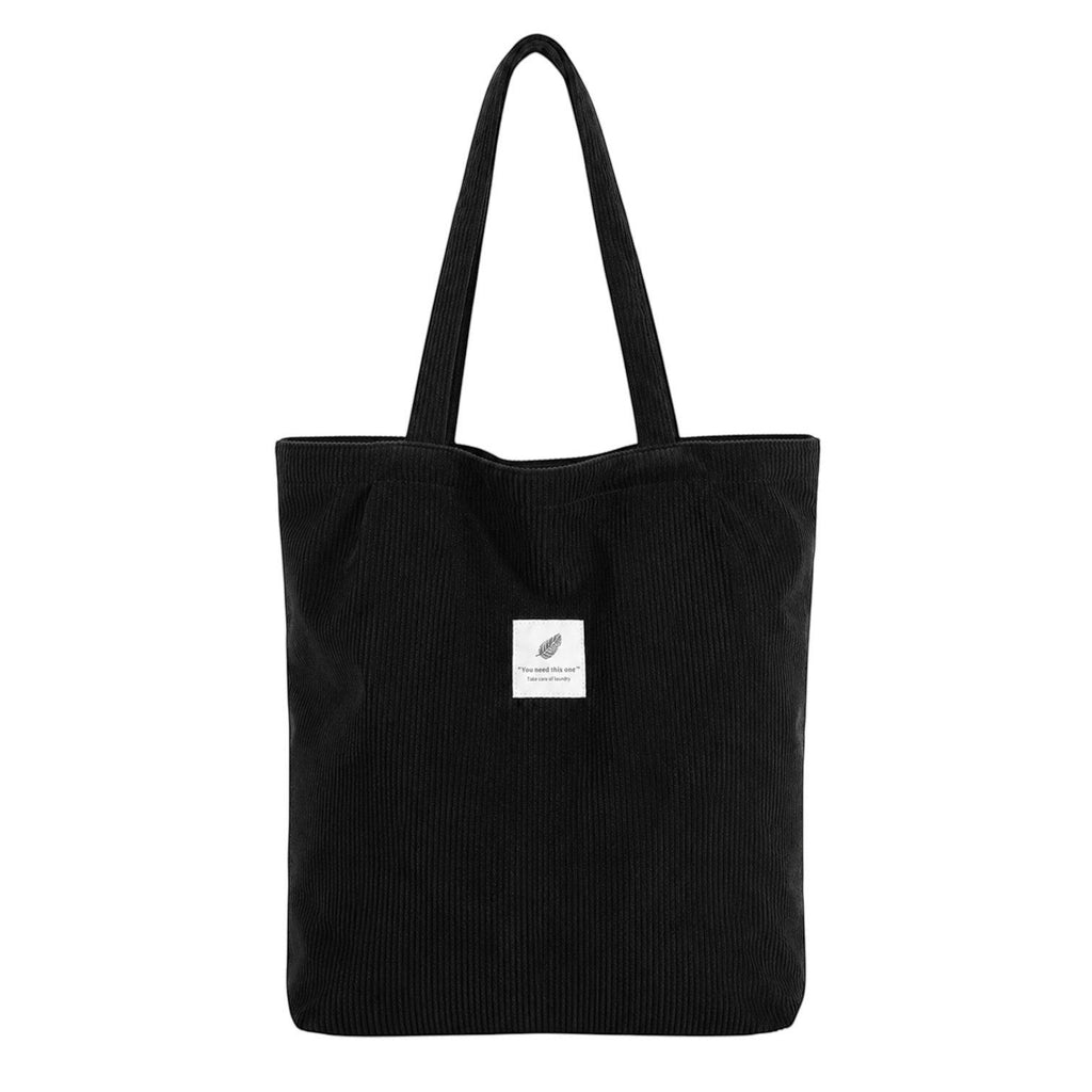 Sac fourre-tout noir en velours côtelé Univers Sac avec deux anses et une petite étiquette décorative.