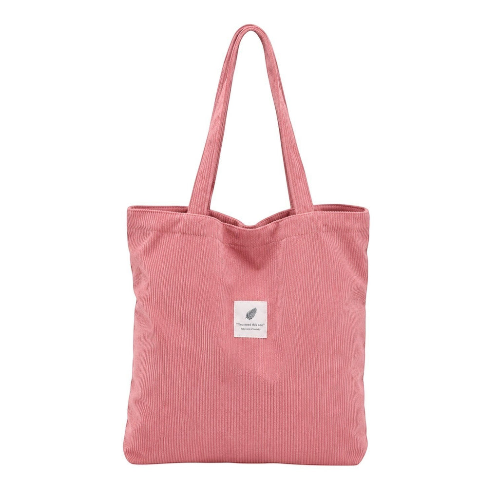 Sac fourre-tout rose en velours côtelé Univers Sac avec deux anses et une petite étiquette décorative.