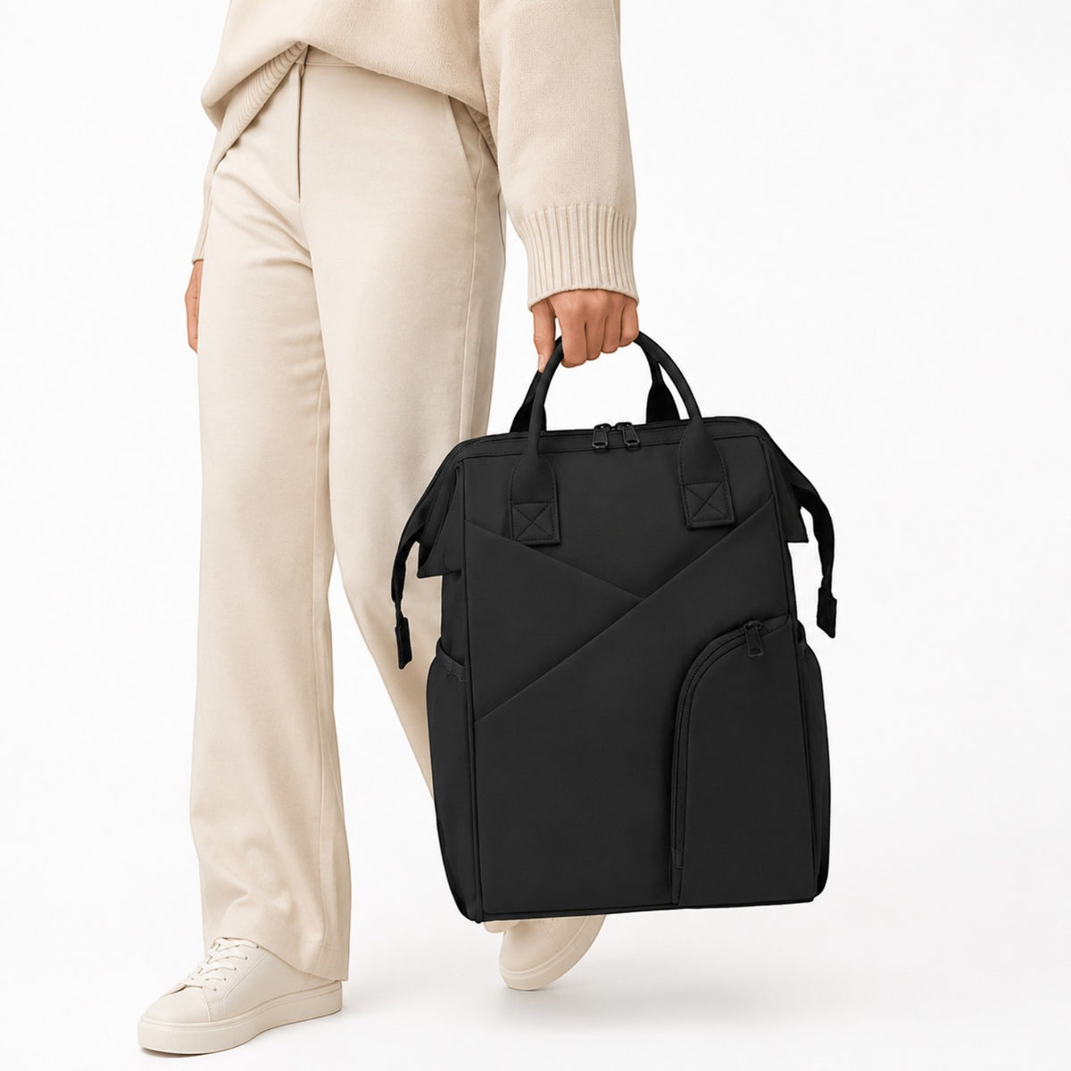 Sac à langer Univers Sac noir spacieux porté à la main par une femme en tenue décontractée beige