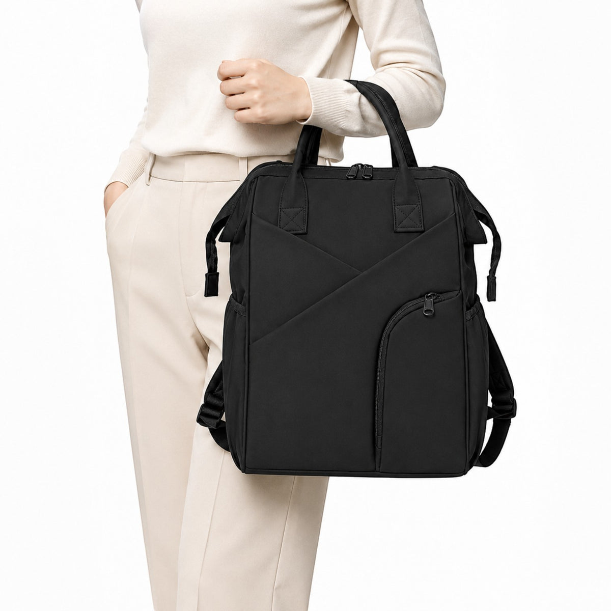 Sac à langer Univers Sac noir en tissu avec fermeture éclair, porté à la main par une femme en tenue élégante