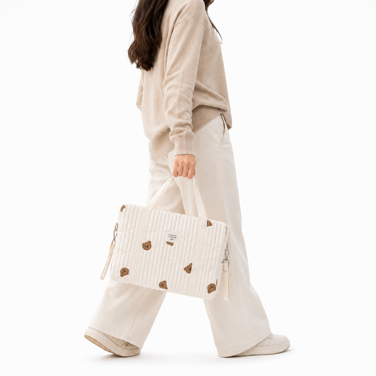 Sac à langer Univers Sac blanc matelassé avec broderies d'ours, style coréen, porté à la main par une femme.