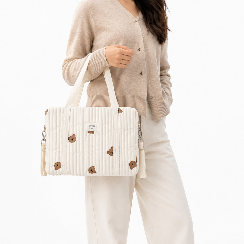 Sac à langer Univers Sac blanc matelassé avec broderies d'oursons, style coréen, porté à la main par une femme.