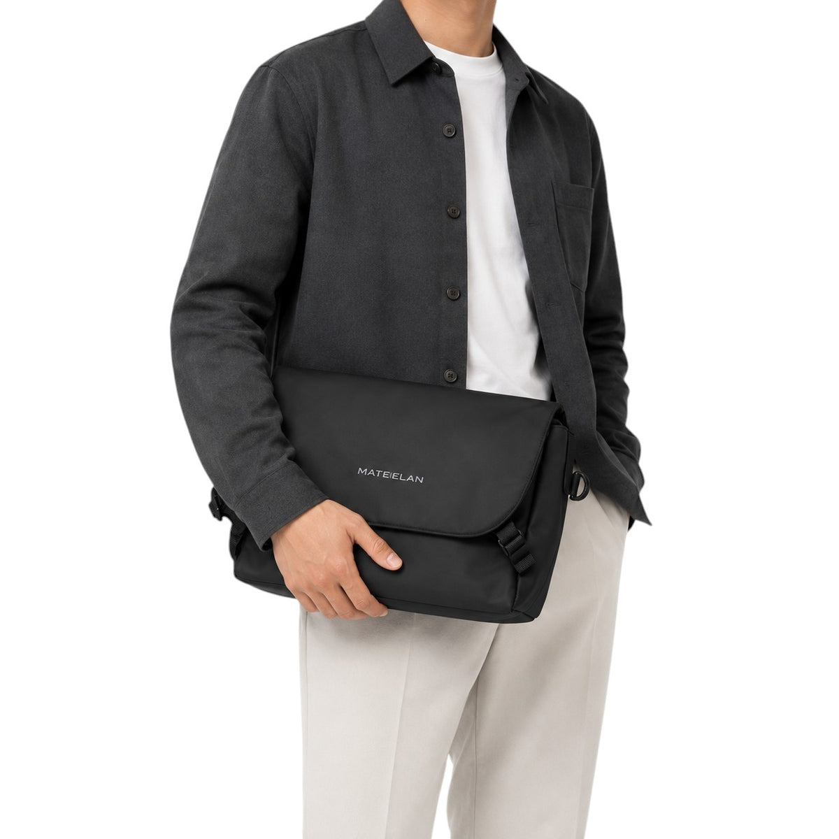 Sac messager noir imperméable Univers Sac en tissu Oxford pour ordinateur portable, porté à la main par un homme.