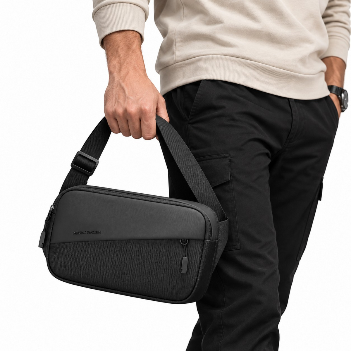 Sacoche bandoulière noire MARK RYDEN en tissu Oxford imperméable, tenue à la main, style urbain et minimaliste.